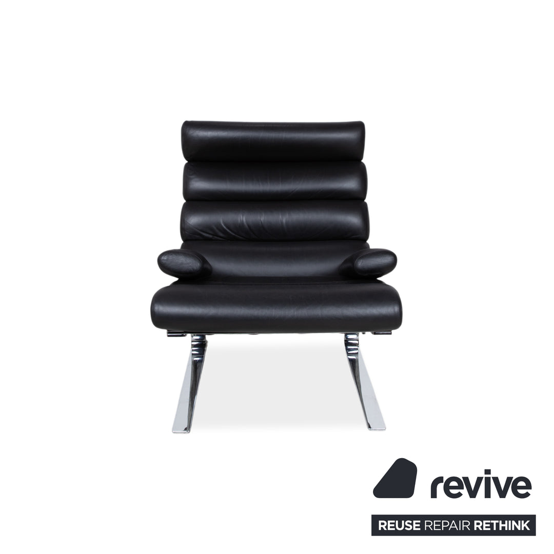 Fauteuil Cor Sinus en cuir chromé noir avec repose-pieds et bras articulés.