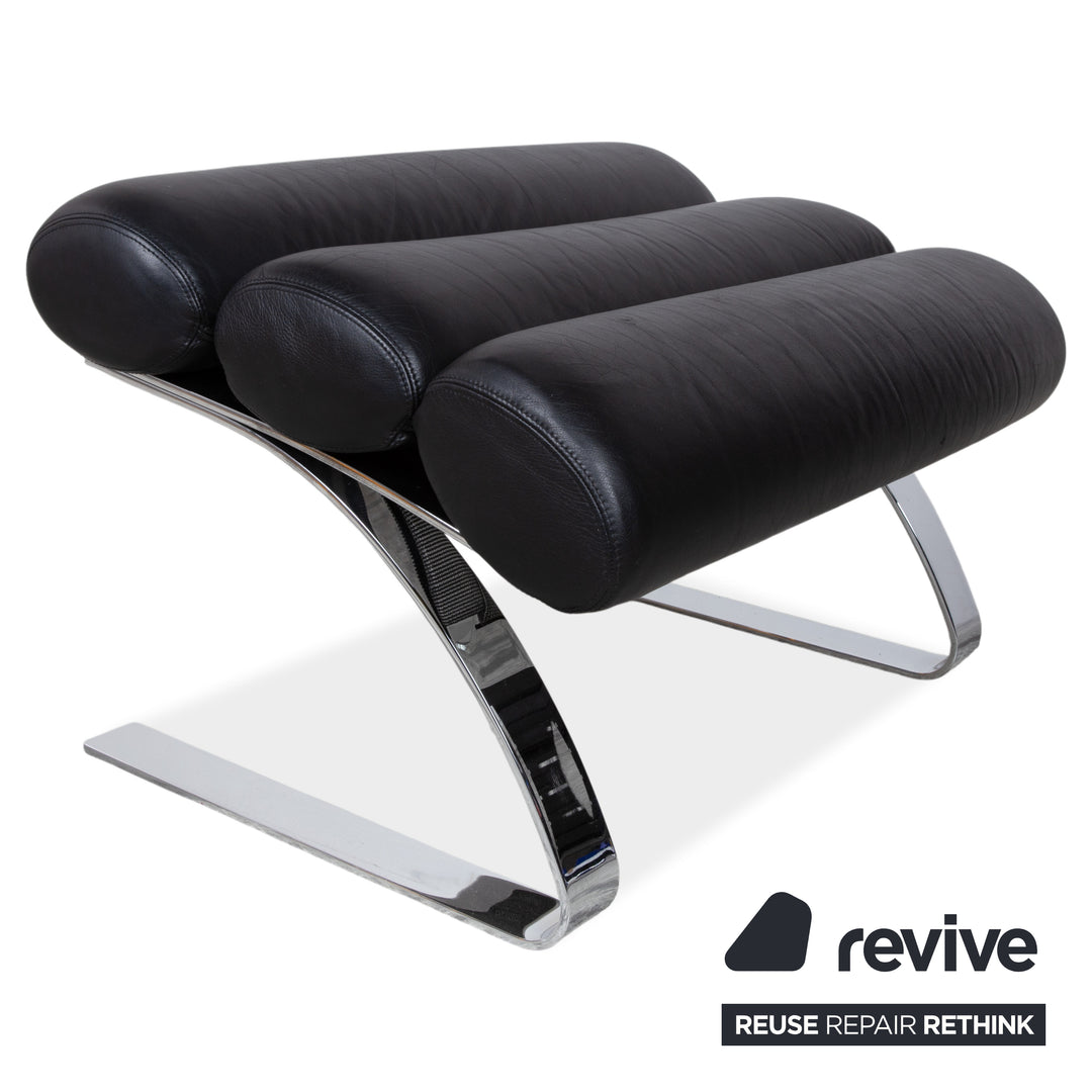 Fauteuil Cor Sinus en cuir chromé noir avec repose-pieds et bras articulés.
