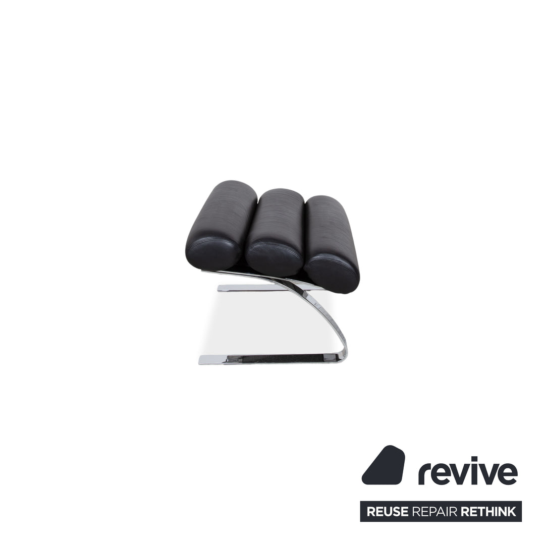 Fauteuil Cor Sinus en cuir chromé noir avec repose-pieds et bras articulés.