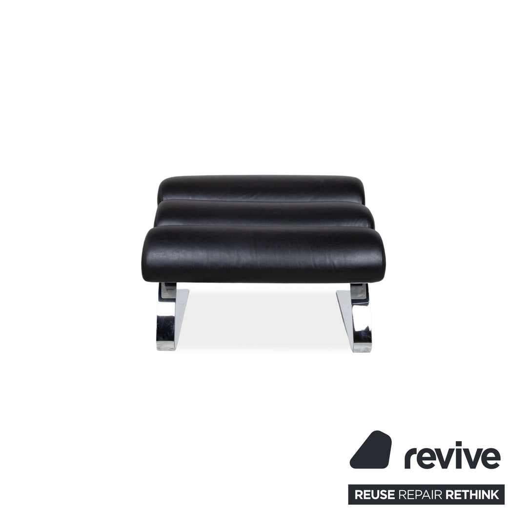 Fauteuil Cor Sinus en cuir chromé noir avec repose-pieds et bras articulés.