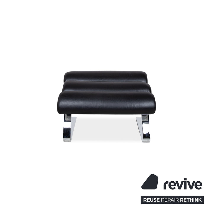 Fauteuil Cor Sinus en cuir chromé noir avec repose-pieds et bras articulés.