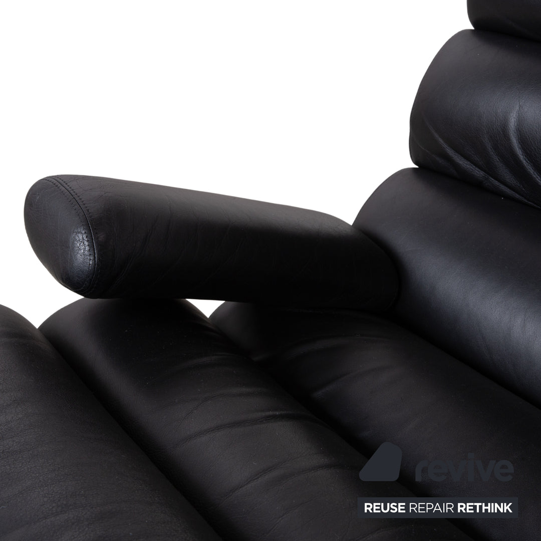 Fauteuil Cor Sinus en cuir chromé noir avec repose-pieds et bras articulés.
