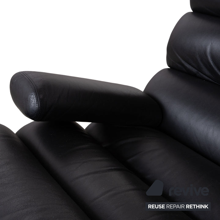 Fauteuil Cor Sinus en cuir chromé noir avec repose-pieds et bras articulés.